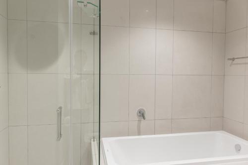 La salle de bains blanche est pourvue d'une douche et d'une baignoire. dans l'établissement Thee LuX Ellipse Waterfall, à Midrand