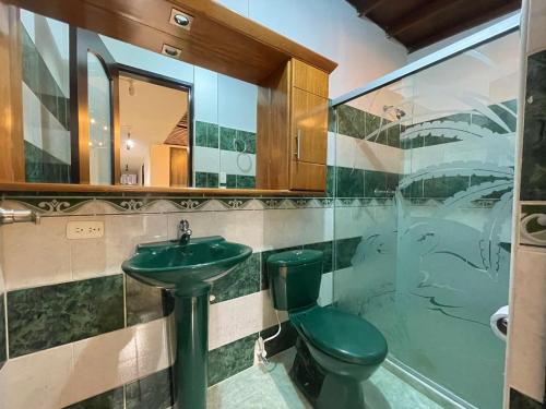 baño con aseo verde y lavamanos en Casa Meraki, en Medellín
