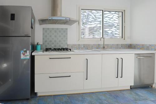 une cuisine avec des armoires blanches et un réfrigérateur en acier inoxydable dans l'établissement Villa OCEANSIDE Lège CAP-FERRET, à Lège-Cap-Ferret