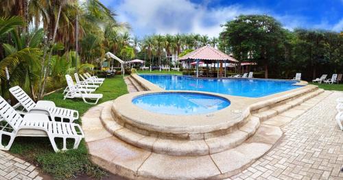 a swimming pool with white lounge chairs and a resort at Hotel Las Palmas in Coco