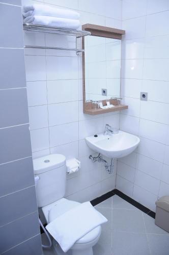 IDEA's Hotel Jalan Ibrahim Aji في باندونغ: حمام ابيض مع مرحاض ومغسلة