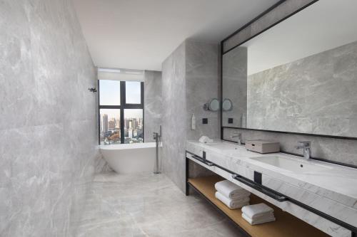 a bathroom with a tub and a sink and a mirror at Fairfield by Marriott Huai'an Downtown in Huai'an