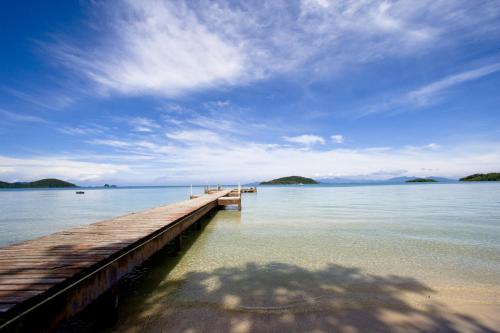 a wooden dock in the water with mountains in the background at Koh Mak Resort in Ko Mak
