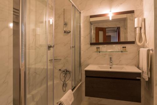a bathroom with a shower and a sink and a mirror at Pao de Acucar Hotel in Porto