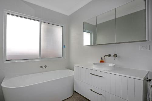 ein weißes Badezimmer mit einem Waschbecken und einem Spiegel in der Unterkunft The Beach Nest in Hawks Nest