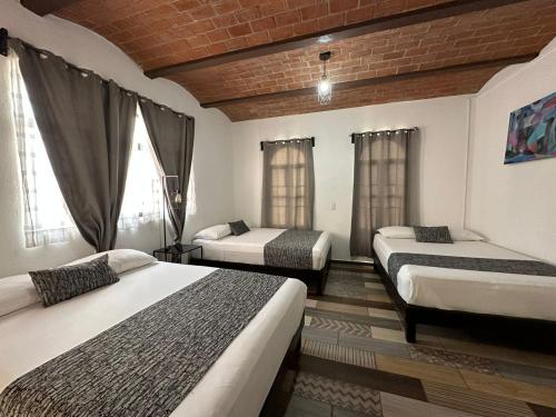 Cette chambre comprend 3 lits et un mur en briques. dans l'établissement Casa Malva Sweet Stay, à Guanajuato
