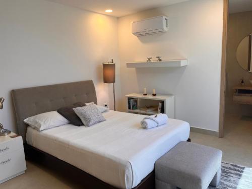 a bedroom with a large white bed and a stool at Ocean Club Resort Beach House in Juan de Acosta