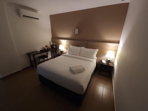 a bedroom with a white bed with two tables and two lamps at Yu Hotel Chinatown in Kuala Lumpur