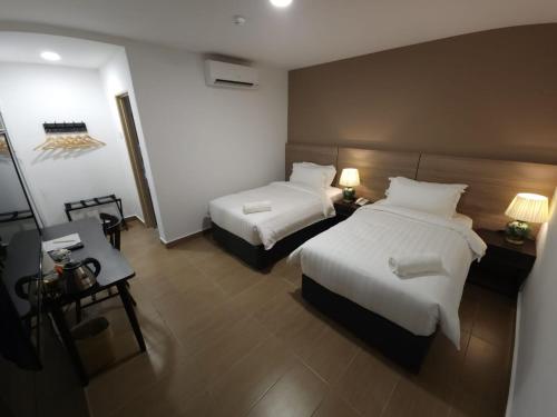 a hotel room with two beds and a table at Yu Hotel Chinatown in Kuala Lumpur