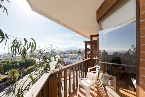 a balcony with a white chair looking out at the mountains at Linda Vista Apart Hotel in Concón