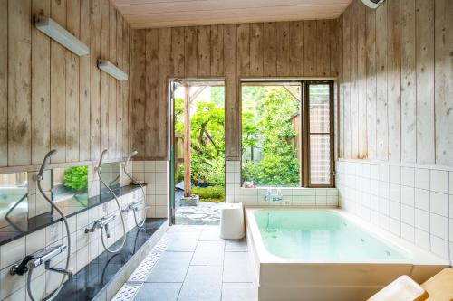 ootaryokan في Kuroki: حمام مع حوض كبير ونافذة كبيرة