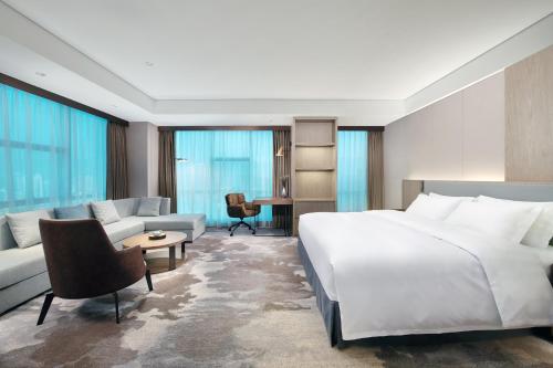 a bedroom with a large white bed and a couch at Empark Grand Hotel Fuzhou in Fuzhou