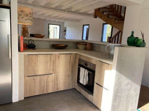 une cuisine avec des armoires en bois et un réfrigérateur dans l'établissement Maison lumineuse en pleine nature, 800 m de la mer, proche plage, jardin, WiFi, tout équipé. - FR-1-418-229, à Locmaria