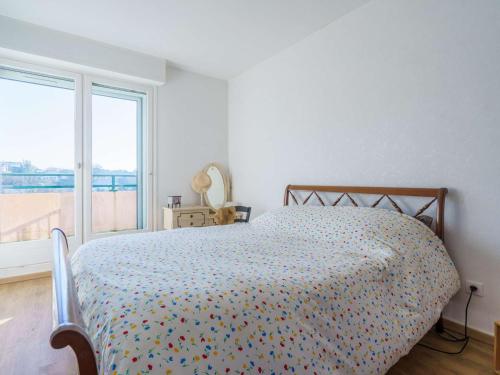 sypialnia z łóżkiem z kolorową kołdrą i oknem w obiekcie Grand appartement 2 chambres avec terrasse à Saint-Jean-de-Luz - FR-1-4-667 w mieście Saint-Jean-de-Luz