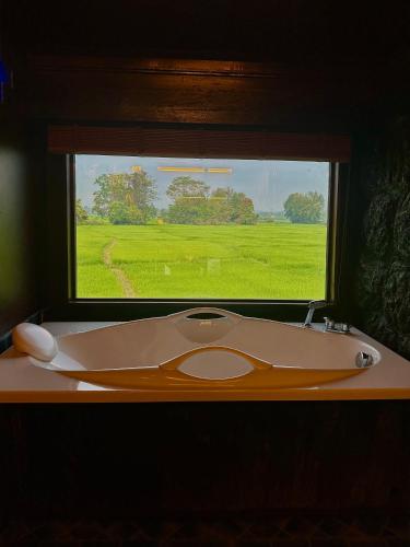 a bathroom with a sink and a window with a green field at Bantunglom Resort in Mae Rim