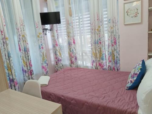 een slaapkamer met een roze bed en een raam bij Quirino hub 2 BR family room in Davao City