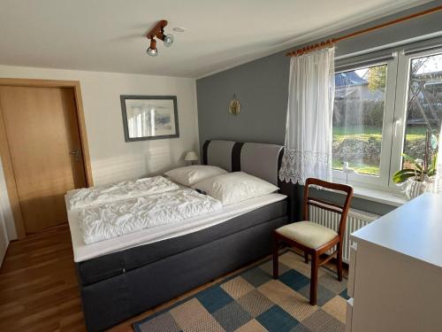 a bedroom with a bed and a chair and a window at Cozy Holiday Home in Hohenkirchen near Baltic Sea in Hohenkirchen