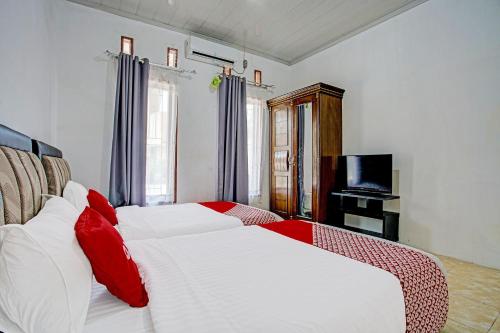 ein Schlafzimmer mit einem großen weißen Bett mit roten Kissen in der Unterkunft Capital O 92358 Pondok Amak Syariah in Padang