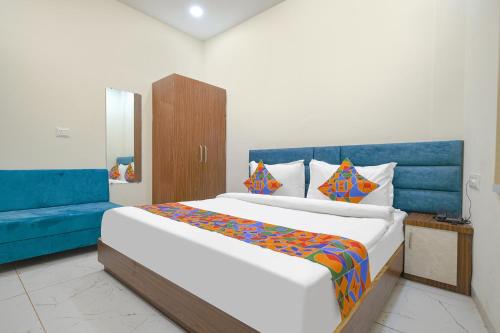 a bedroom with a large bed and a blue couch at FabHotel Ramya in Indore
