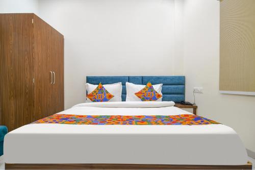 a bedroom with a large bed with a blue headboard at FabHotel Ramya in Indore