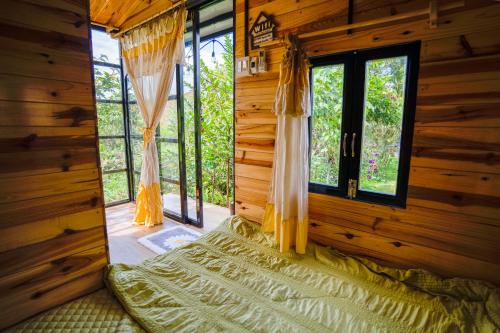 a room with a bed in a wooden cabin with windows at HomeTa Homestay in Bao Loc