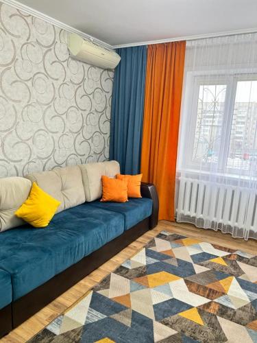 a living room with a blue couch with colorful pillows at Квартира бизнес класса in Semey