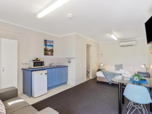 a living room with a kitchen and a bed at Top Spot Motel in Maroochydore