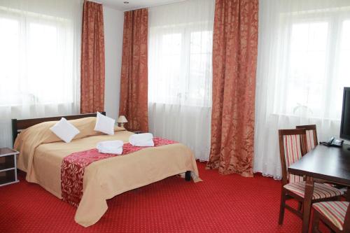 a bedroom with a bed with a red carpet at Hotel Kaprys in Świdnik