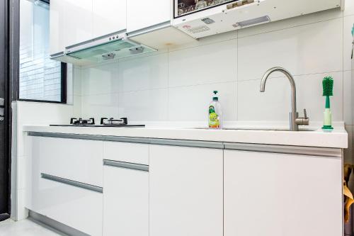 a kitchen with white cabinets and a sink at 綠舍睡到民宿 in Taitung City