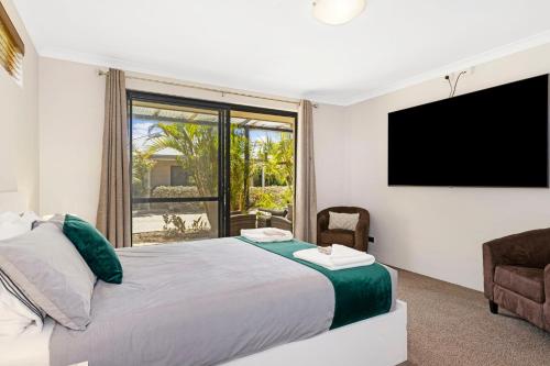 a bedroom with a large bed and a flat screen tv at Baudins of Busselton Bed and Breakfast - Adults only in Busselton