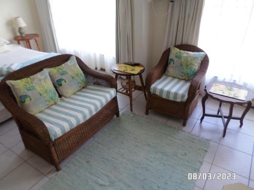 a room with two chairs and a couch and a bed at Hermanus At Rikis Self Catering in Hermanus