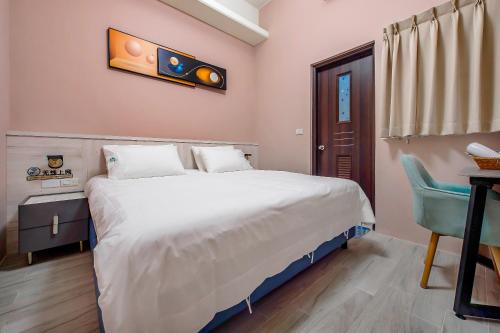 a bedroom with a large white bed and a desk at 綠舍睡到民宿 in Taitung City