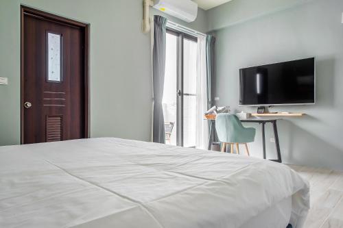 a bedroom with a bed and a flat screen tv at 綠舍睡到民宿 in Taitung City