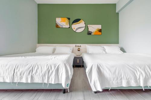 two beds in a room with green walls at 綠舍睡到民宿 in Taitung City
