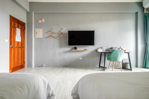 a bedroom with a bed and a desk with a tv at 綠舍睡到民宿 in Taitung City