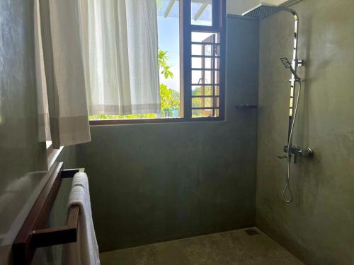 uma casa de banho com um chuveiro e uma janela em Atteriya HILLTOP em Matara