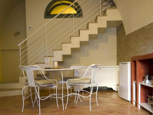 una sala da pranzo con tavolo, sedie e scale di Casa Vacanza "Nel Cuore dei Sassi" a Matera