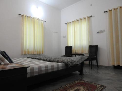 a bedroom with a bed and two chairs and curtains at Jawai Leopard Villa in Bijāpur