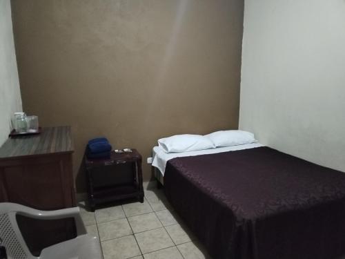 a small bedroom with a bed and a table and a chair at Hotel España in Guatemala