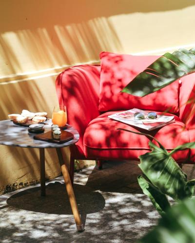 a living room with a red chair and two tables at JM Boutique Hotel in Phu Quoc