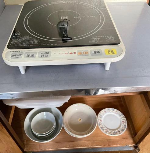 un horno tostador con tazones y platos en un estante en アルピエb202号室 目の前に無料駐車場Wi-Fiあります, en Kumamoto