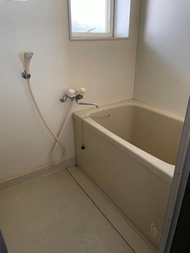 Un baño con bañera y ventana. en アルピエb202号室 目の前に無料駐車場Wi-Fiあります, en Kumamoto