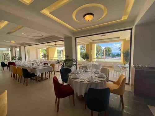 a dining room with white tables and chairs and windows at Luxury 5 Star Suite At Samana W Marina & Ocean Views in Santa Bárbara de Samaná