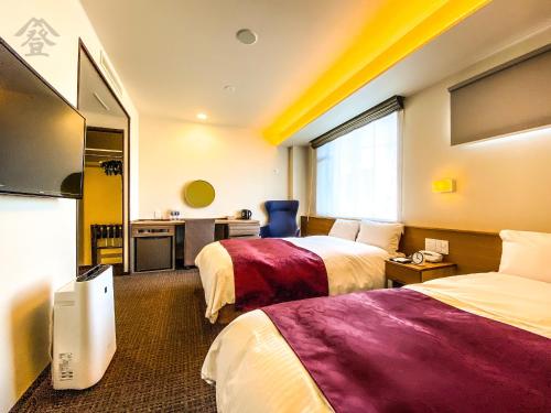 a hotel room with two beds and a television at Hotel Noborisaka in Fujikawaguchiko