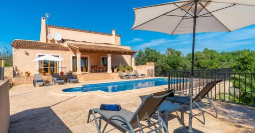 a villa with a pool and a patio with chairs and an umbrella at Villa Rito Nou in Felanitx