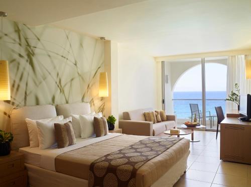 a bedroom with a large bed and a living room at The Ixian Grand & All Suites - Adults Only Hotel in Ixia