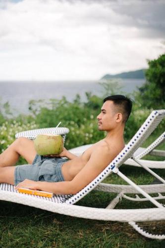 a man sitting in a lawn chair with a cake at Exclusive Cliff House with Pool and Beach Access in Dumanjug