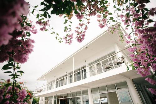 a white building with pink flowers in front of it at Exclusive Cliff House with Pool and Beach Access in Dumanjug
