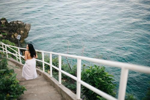 a woman standing on a staircase looking at the ocean at Exclusive Cliff House with Pool and Beach Access in Dumanjug