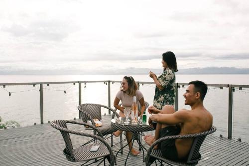 a group of people sitting around a table on a pier at Exclusive Cliff House with Pool and Beach Access in Dumanjug